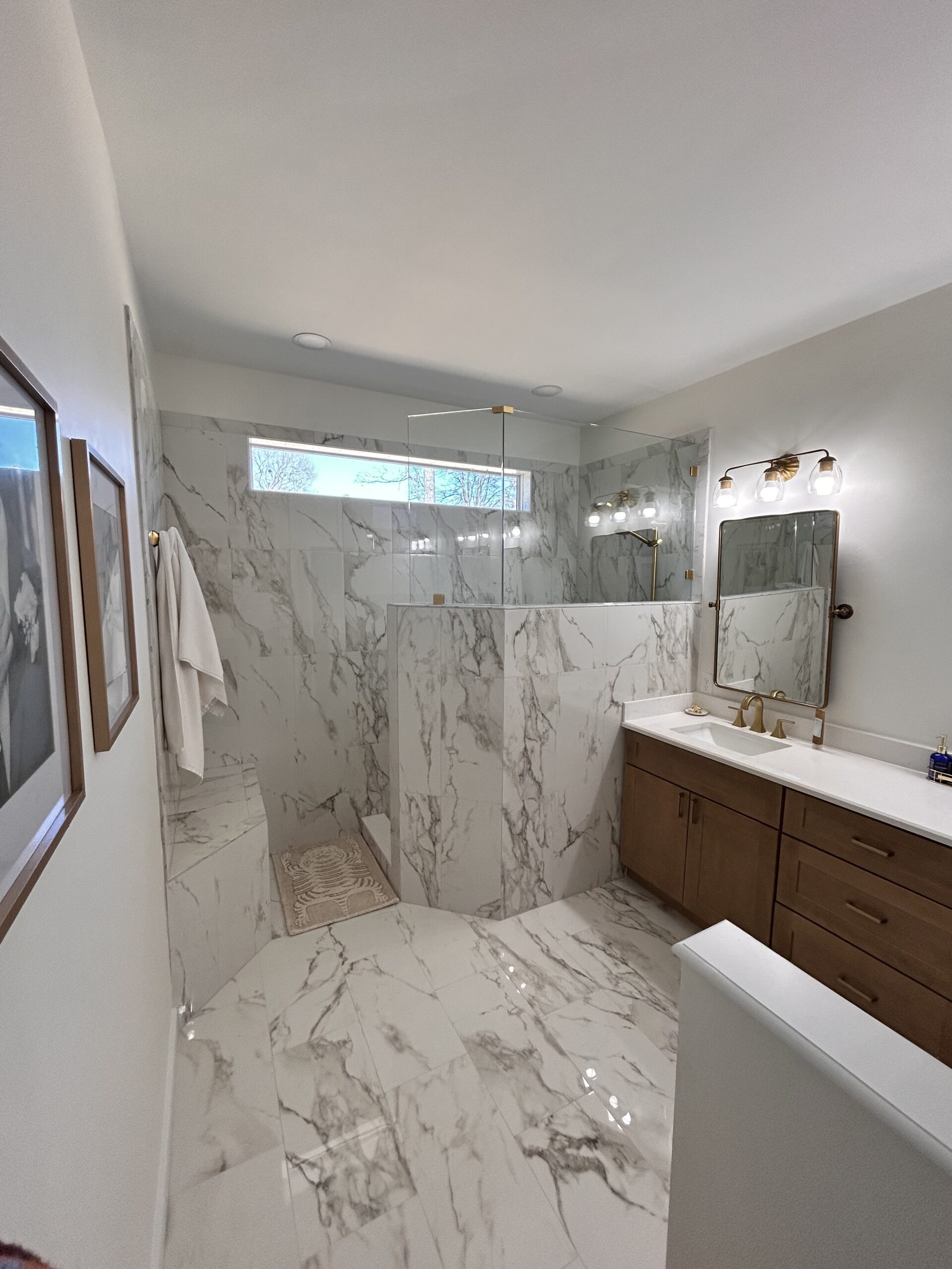 Completed bathroom renovation with coordinated shower, vanity, tile, lighting, and storage details