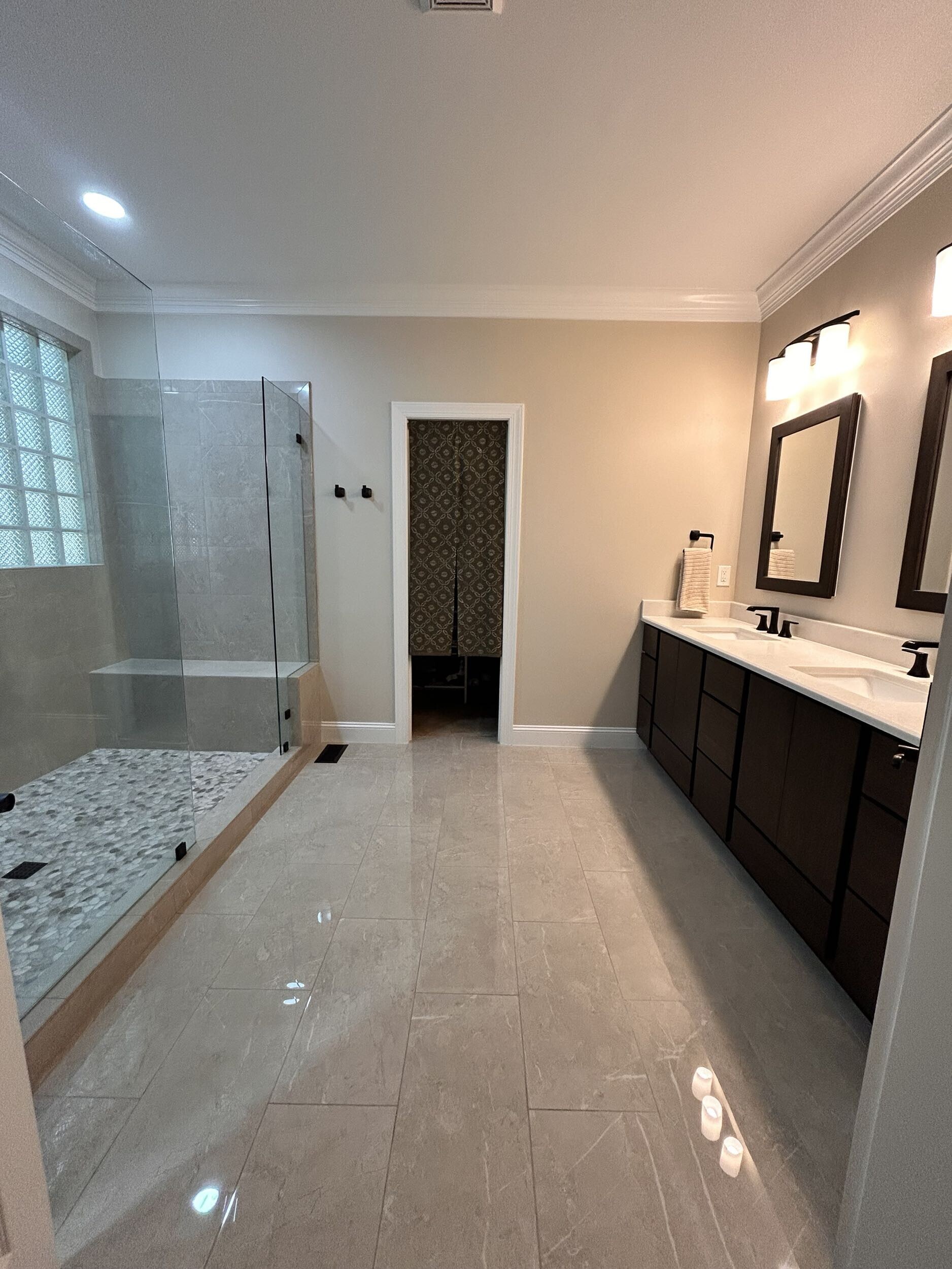 Finished bathroom with a wide circulation path, large glass shower, built-in bench and double vanity